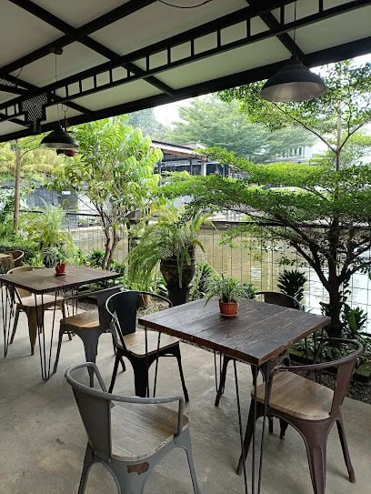 Teras restoran Teras Kayu Manis dengan meja kayu dan pepohonan